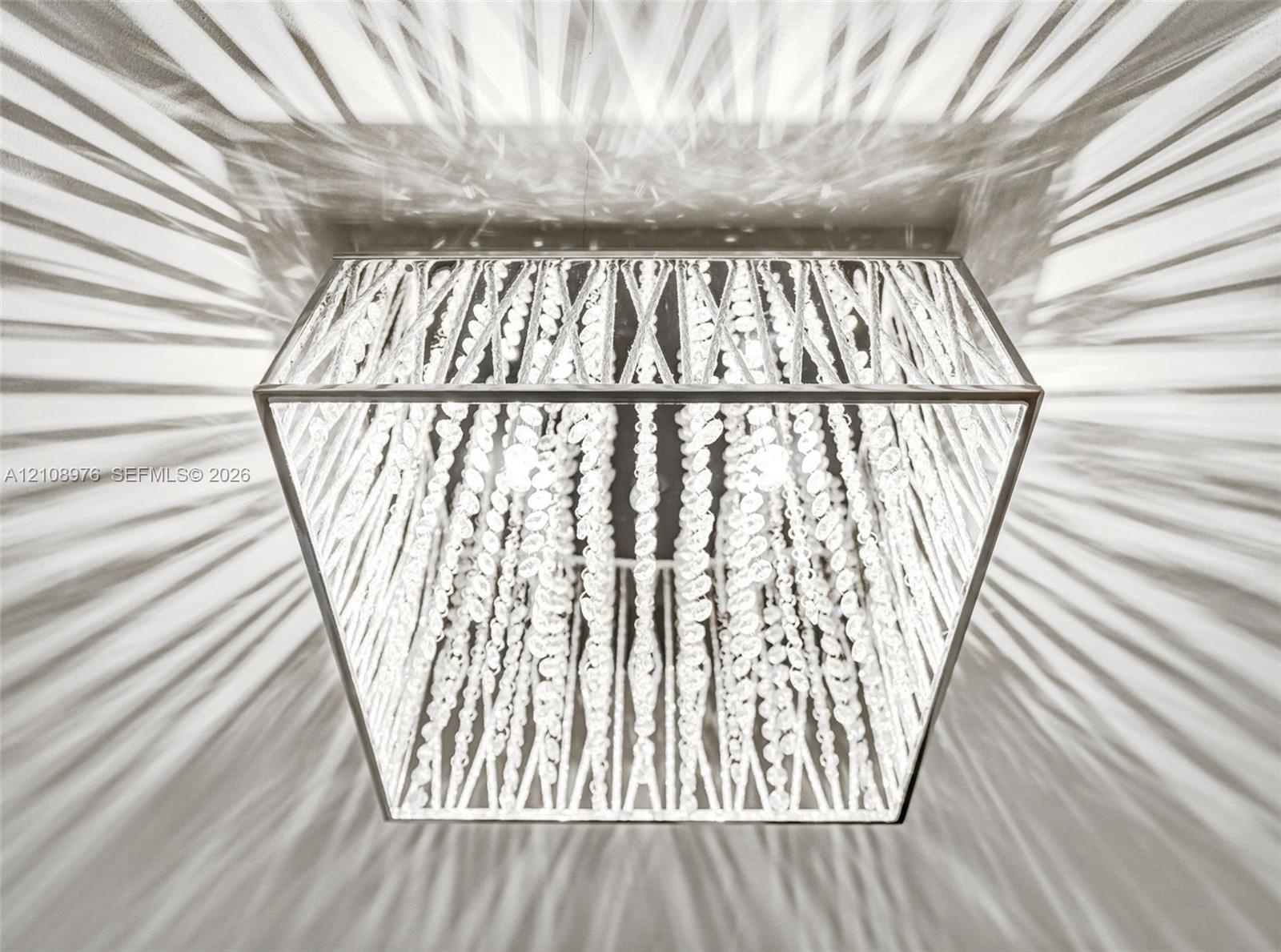 Square flush-mount ceiling fixture featuring a metallic frame and cascading crystal bead strands