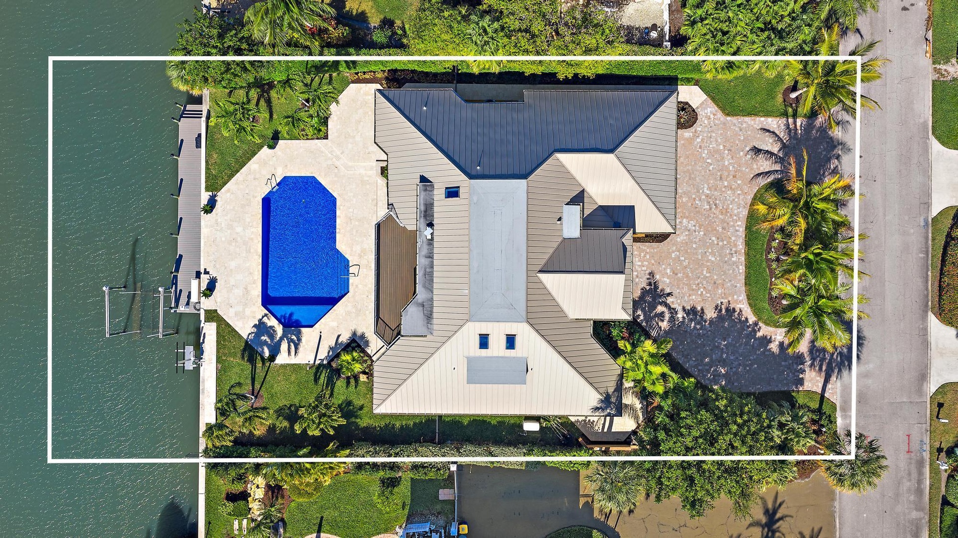 Waterfront property featuring a private dock, expansive paved patio, inground pool, and metal roofing
