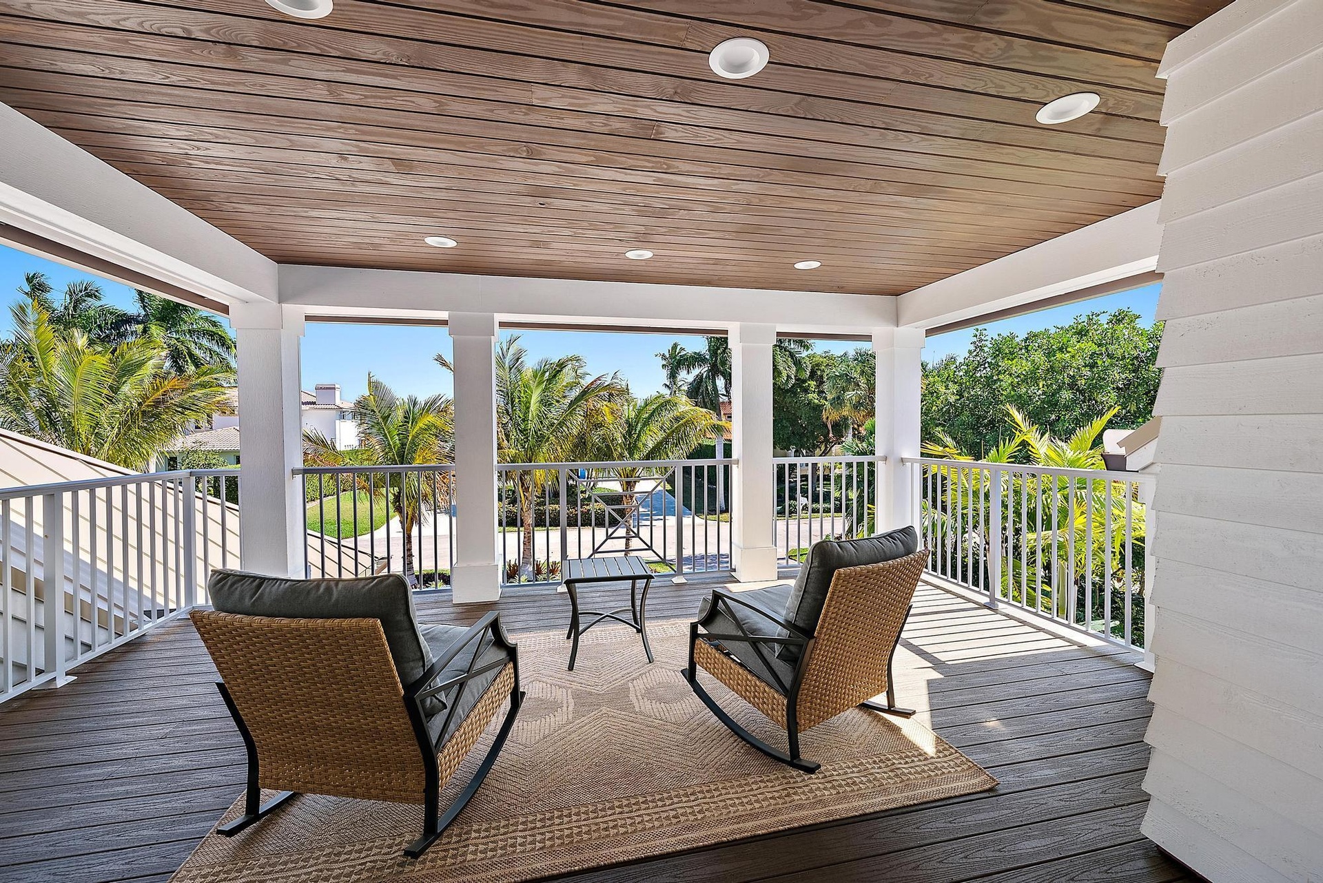 Covered balcony featuring wood-finish ceiling planks, recessed lighting, white railing, and dark composite decking