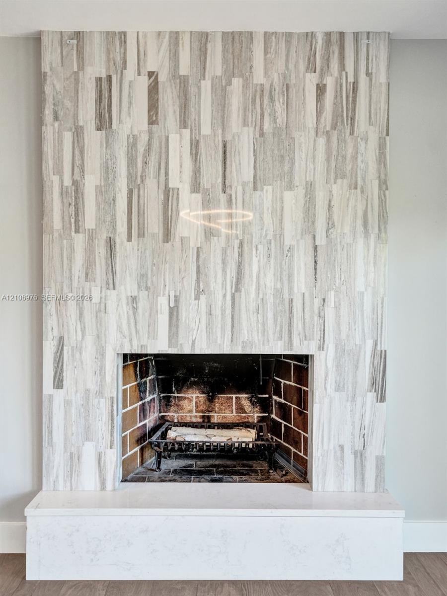 Fireplace featuring floor-to-ceiling vertical tile surround, brick-lined firebox, metal grate, and a solid rectangular hearth