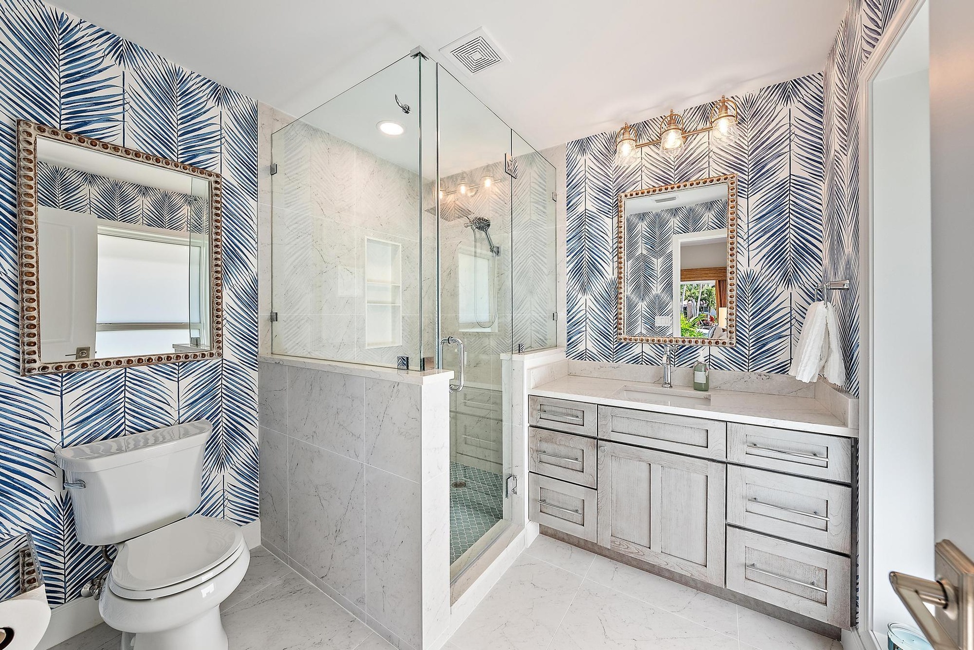 Bathroom featuring a glass-enclosed shower with stone-tile surround, custom wood-finish cabinetry, stone-top vanity, and dual wall-mounted mirrors wit