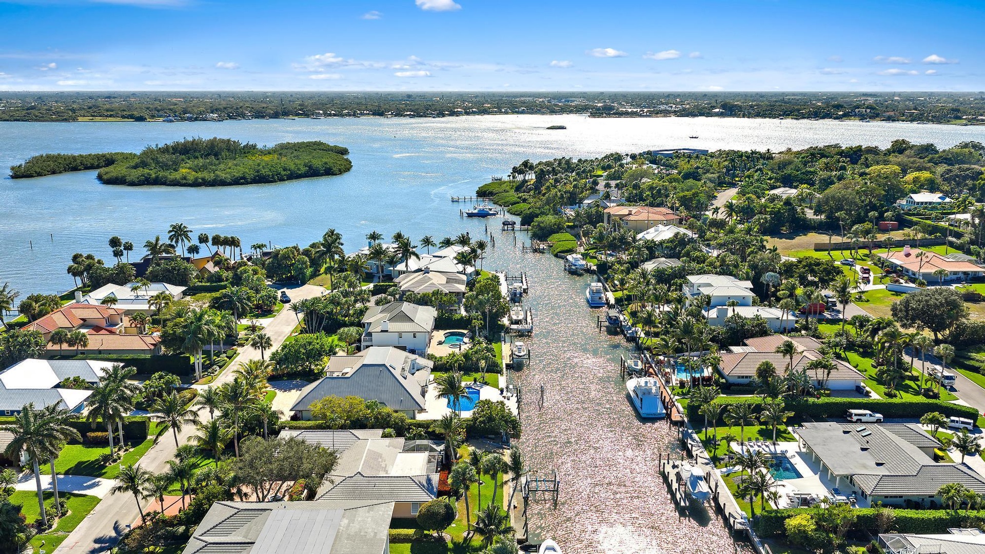 Aerial perspective of a waterfront residential area featuring deep-water canal access, private boat docks, and direct access to open water