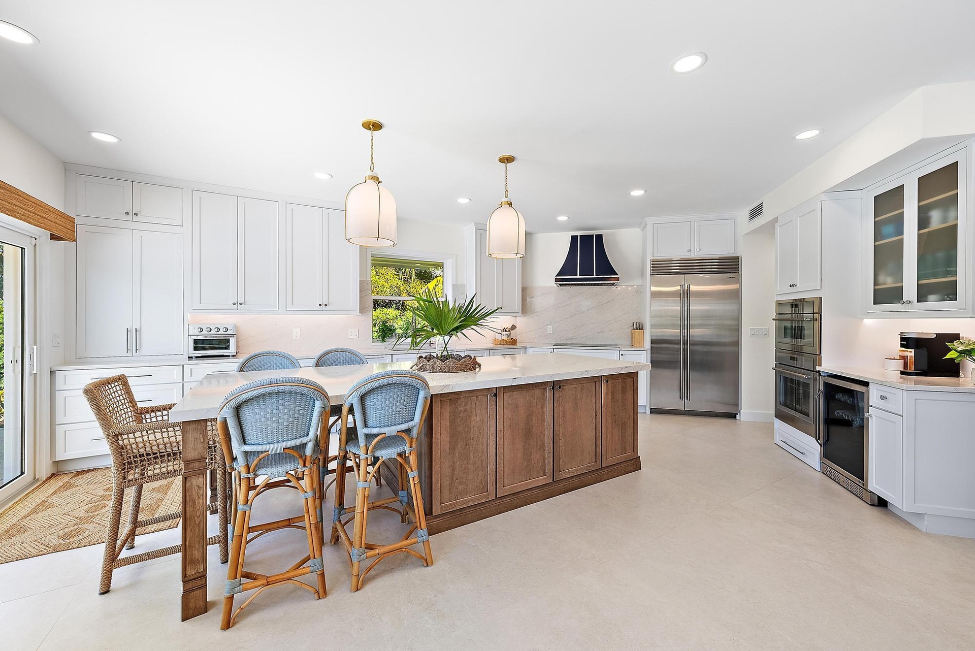 Kitchen featuring white cabinetry, a wood-finish central island with a stone countertop, stainless steel double-door refrigerator, built-in double ove