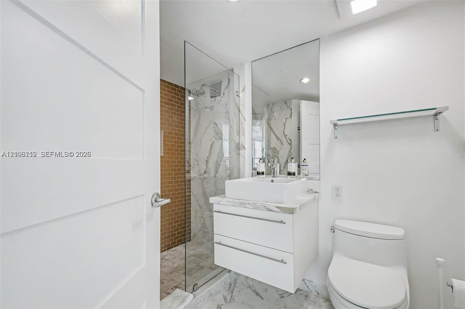 Modern floating vanity with a white vessel sink and stone-finish countertop, walk-in shower with a glass enclosure, floor-to-ceiling mirror, and neutr