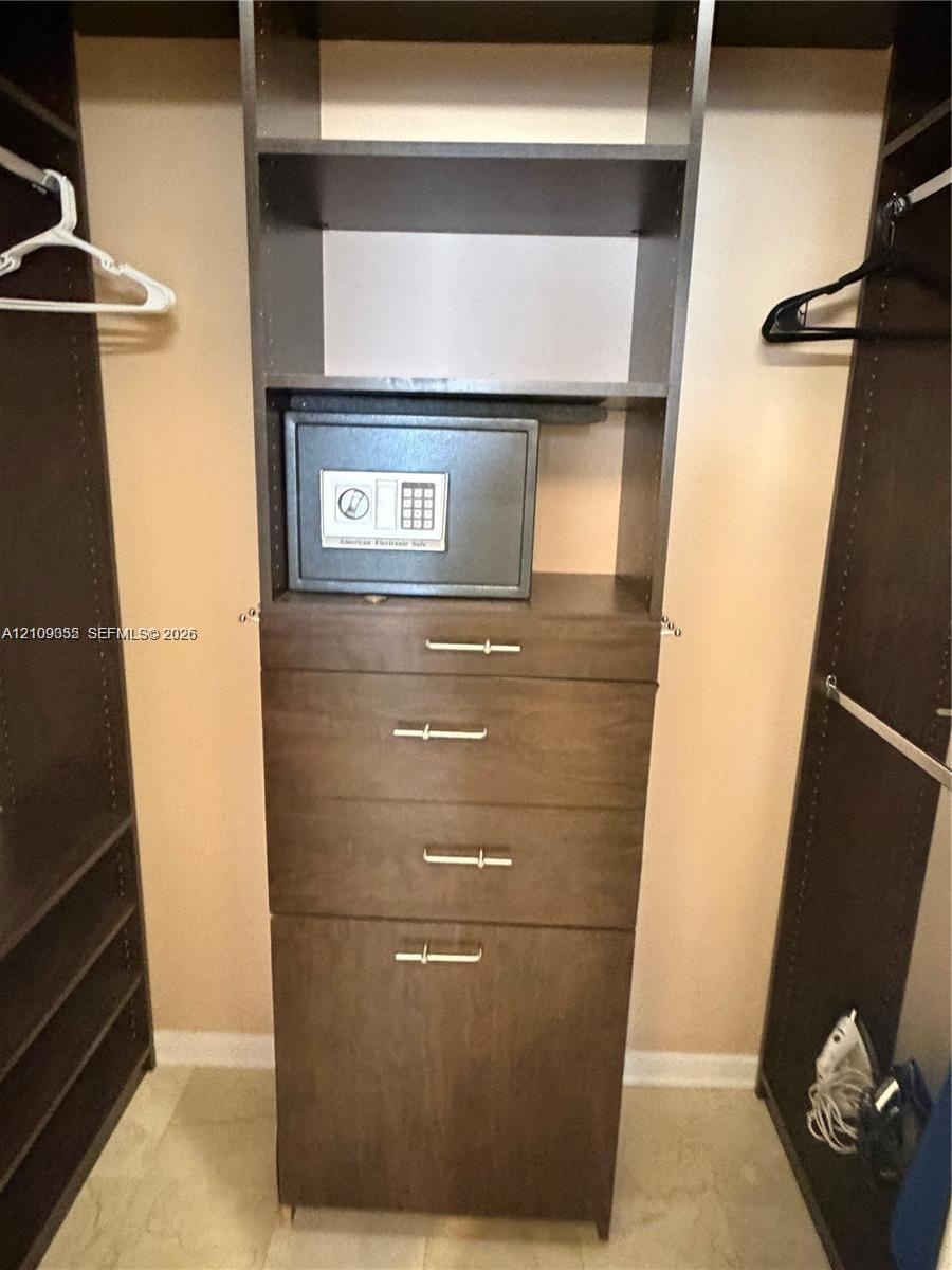 Custom built-in closet organization system featuring dark wood-finish cabinetry, four integrated storage drawers, vertical shelving, and metallic hard