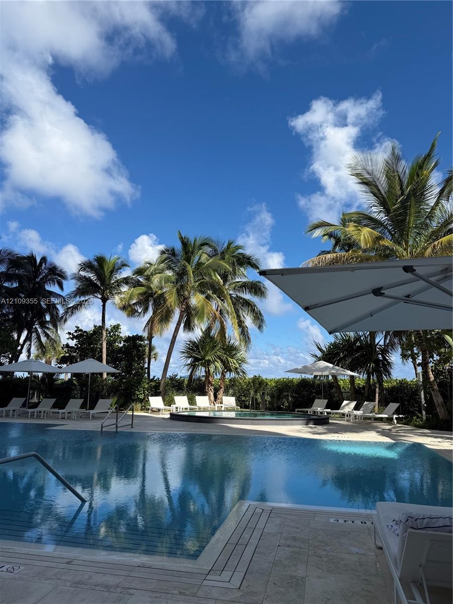 Swimming pool with integrated spa, stone-finish pool deck, and mature palm trees