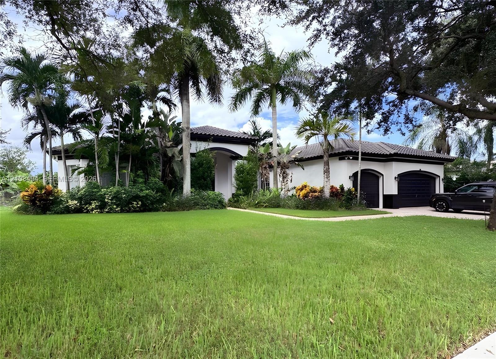 Single-story residence featuring a tile roof, stucco exterior, two-car garage, and mature palm landscaping