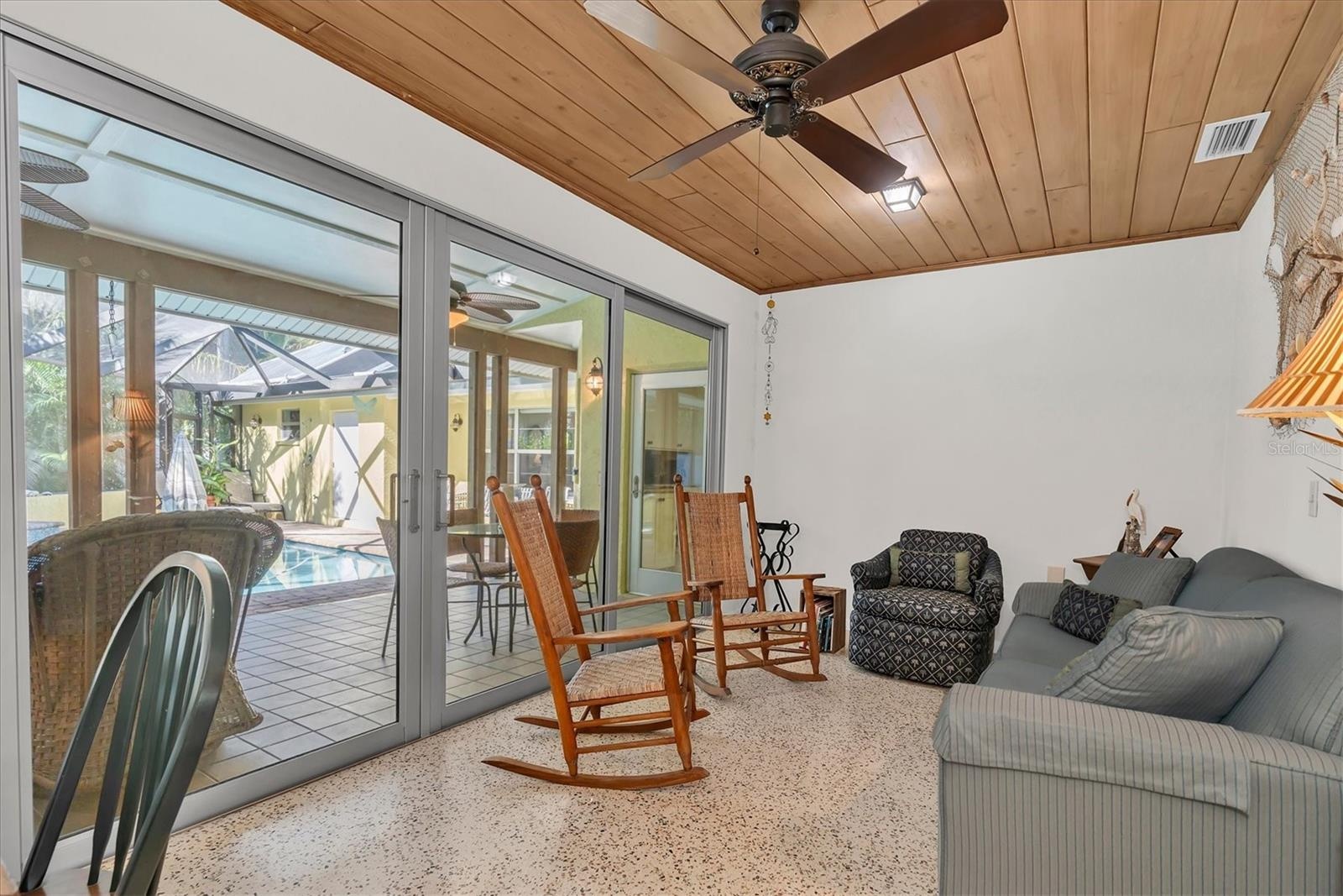Sliders off Florida room open to large covered outdoor dining, cooking and entertaining space