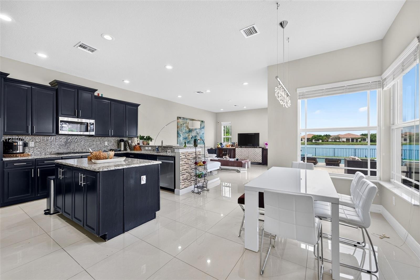 Kitchen featuring dark cabinetry, center island with stone-finish countertop, tiled flooring, stacked stone wall accents, and oversized windows