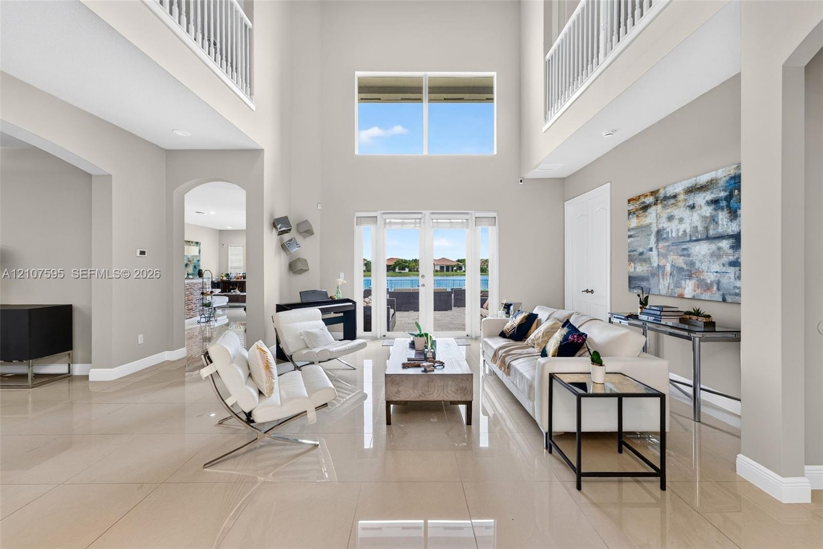 Grand foyer featuring soaring double-height ceilings, large-format tile flooring, a multi-story glass window configuration, arched architectural openi