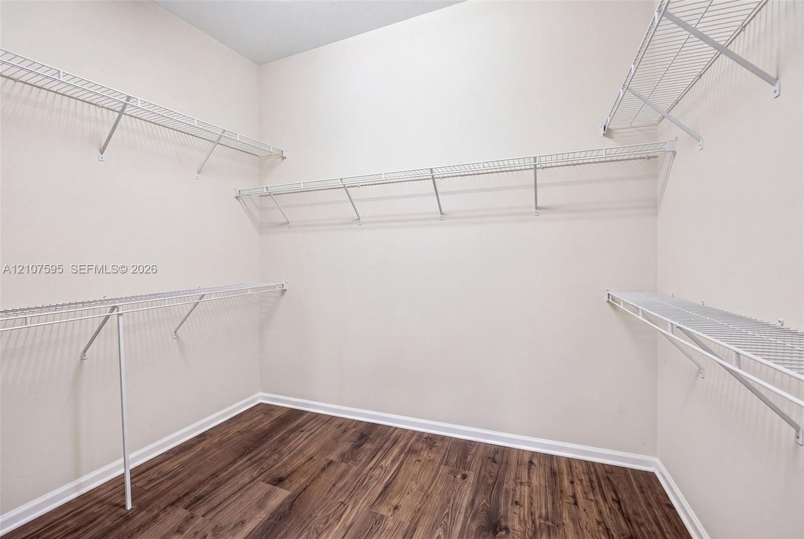 Walk-in closet featuring wood-finish flooring and tiered white wire shelving