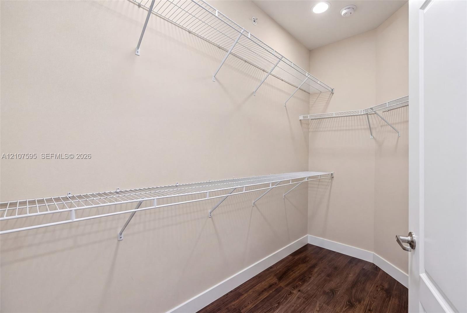 Storage space featuring multi-level white wire shelving and dark wood-finish flooring