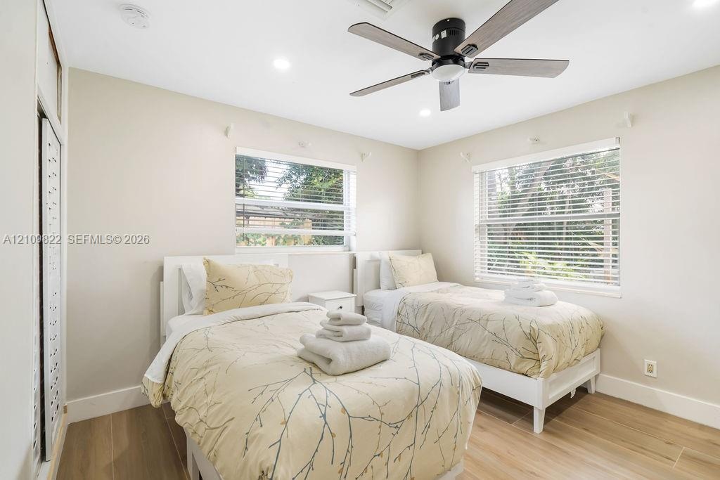Neutral-toned interior featuring wood-finish tile flooring, recessed ceiling lighting, a matte black multi-blade ceiling fan, and horizontal window bl