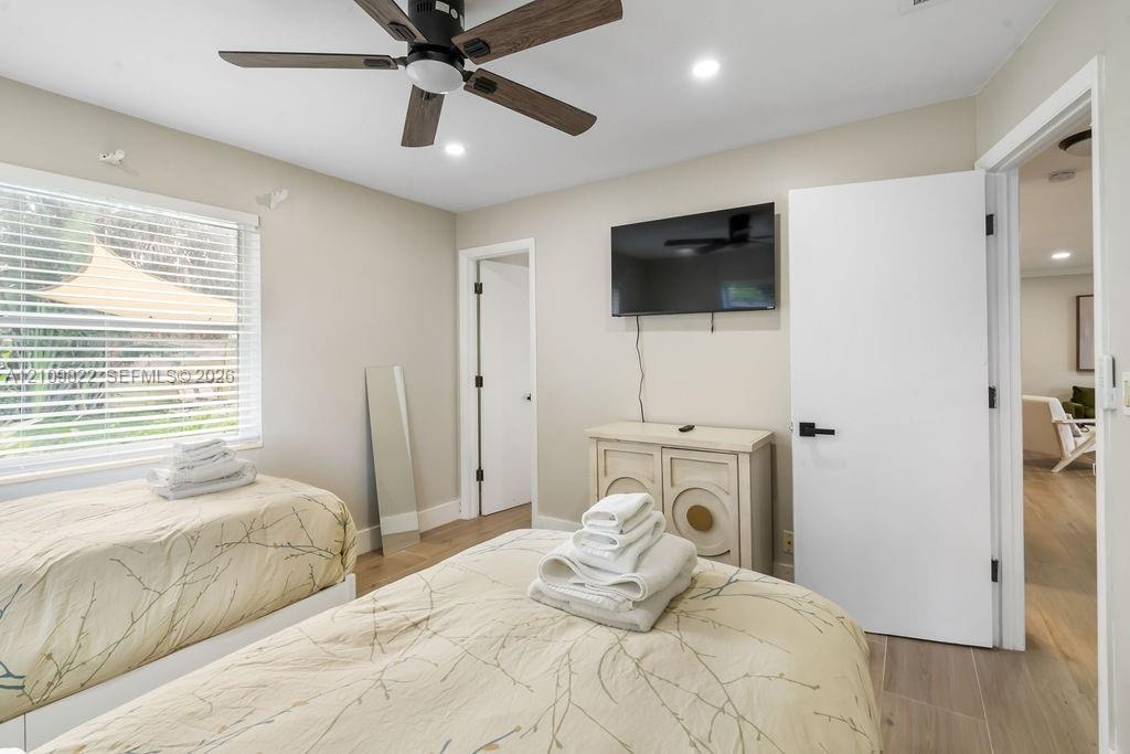 Wood-finish flooring, multi-blade ceiling fan with integrated lighting, recessed lighting, and horizontal slatted window blinds