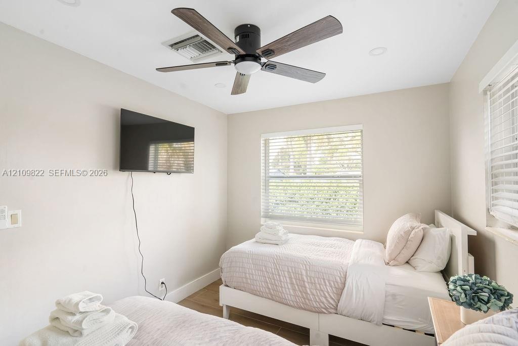 Neutral-toned interior featuring recessed lighting, a modern ceiling fan with wood-finish blades, and windows equipped with horizontal blinds