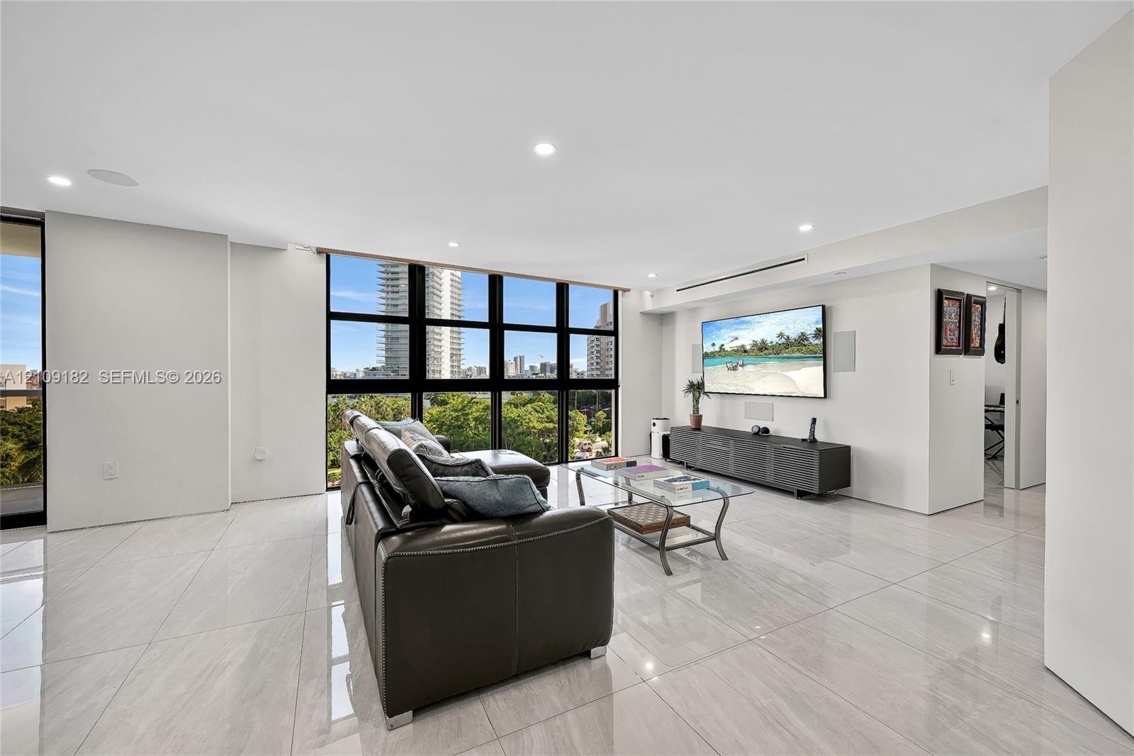 Large-format tile flooring, expansive floor-to-ceiling windows with black mullions, and integrated recessed ceiling lighting