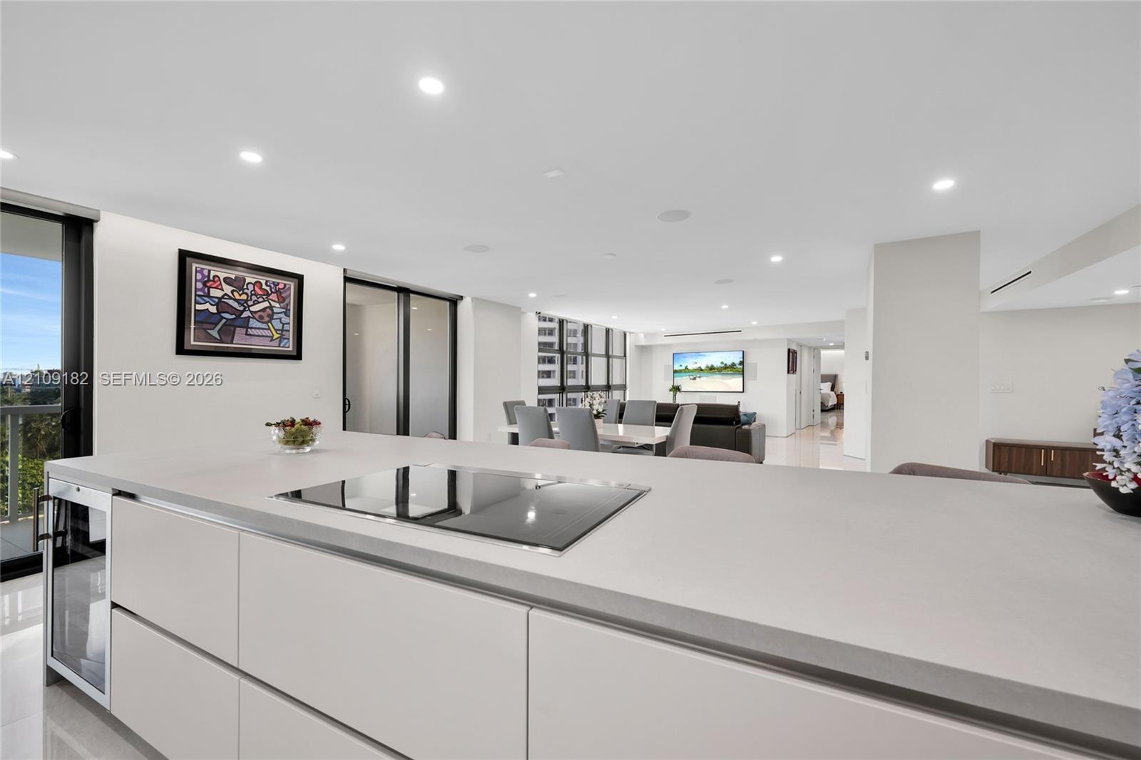 Sleek kitchen featuring flat-panel cabinetry, light-toned stone-surface countertops, built-in stainless steel double wall ovens, a built-in microwave,