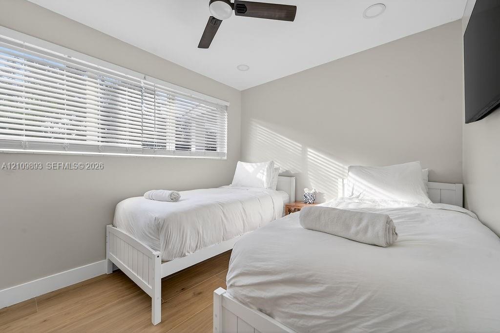 Wood-finish flooring, recessed lighting, ceiling fan with integrated light, and large horizontal window with fitted blinds