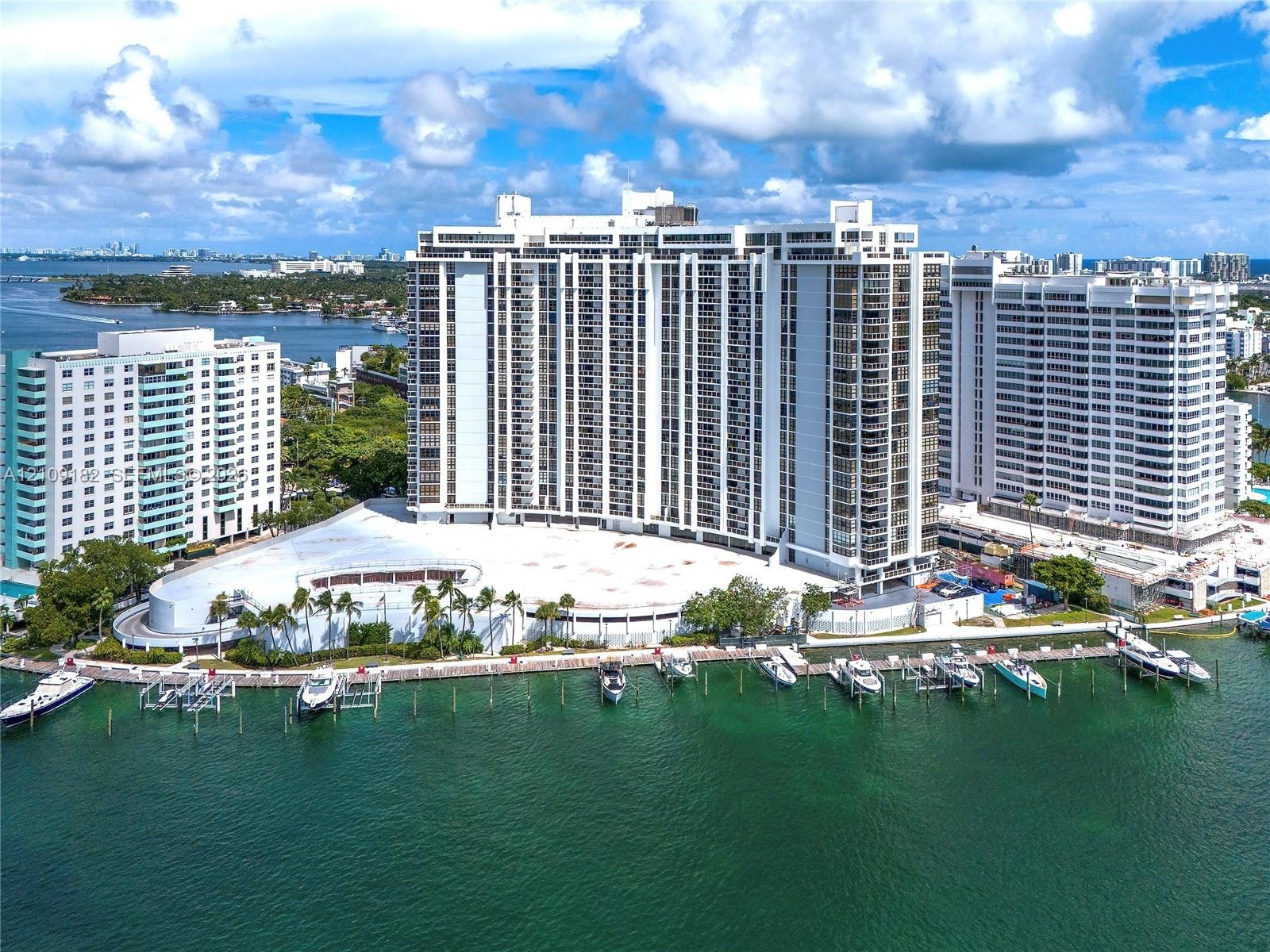 Waterfront wooden dock featuring integrated boat slips, mooring cleats, and proximity to maintained landscaping and palm trees
