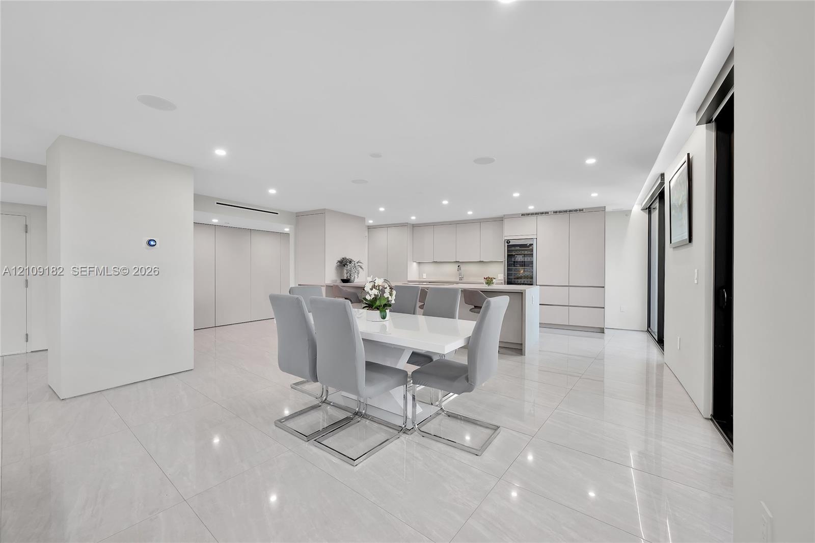 Open-concept interior featuring large-format tile flooring, recessed ceiling lighting, and built-in cabinetry with integrated wine storage
