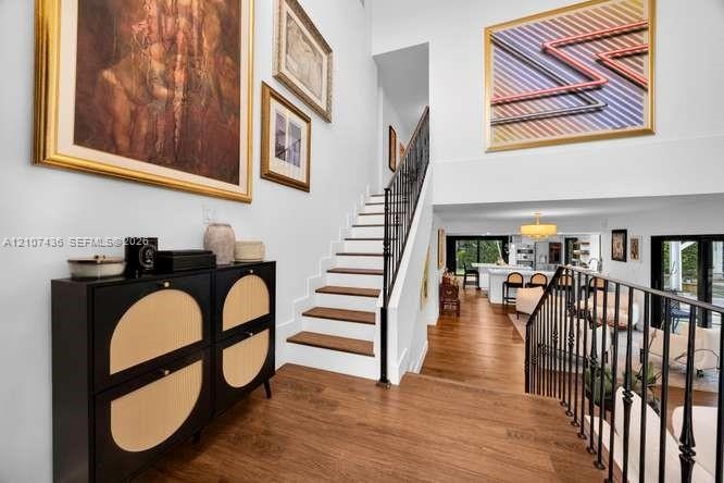 Foyer featuring a high ceiling, wood-finish flooring, and a staircase with wood treads and a black metal railing