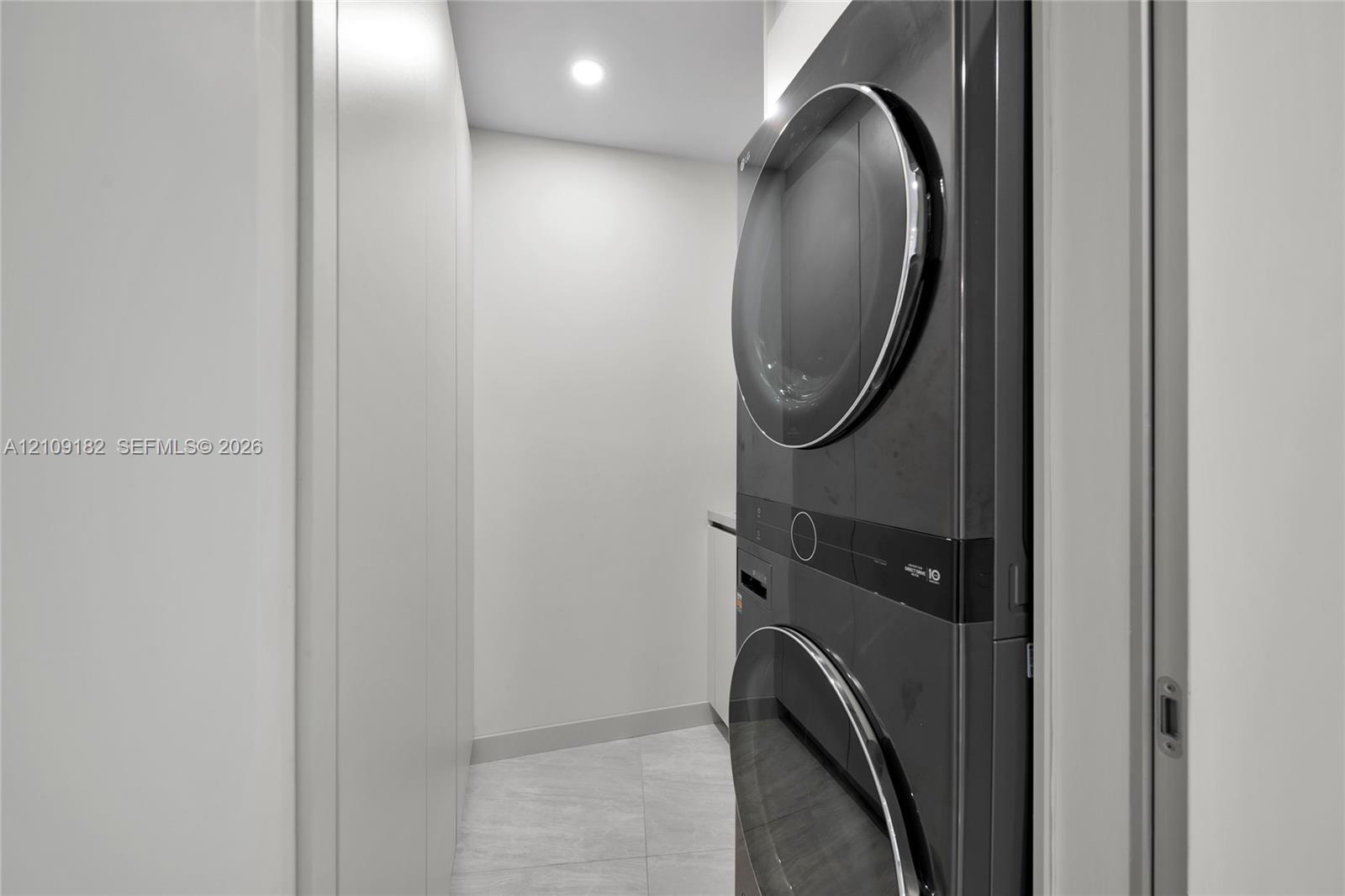 Built-in white cabinetry, integrated desk, light-tone tile flooring, floor-to-ceiling windows, and wall-mounted shelving