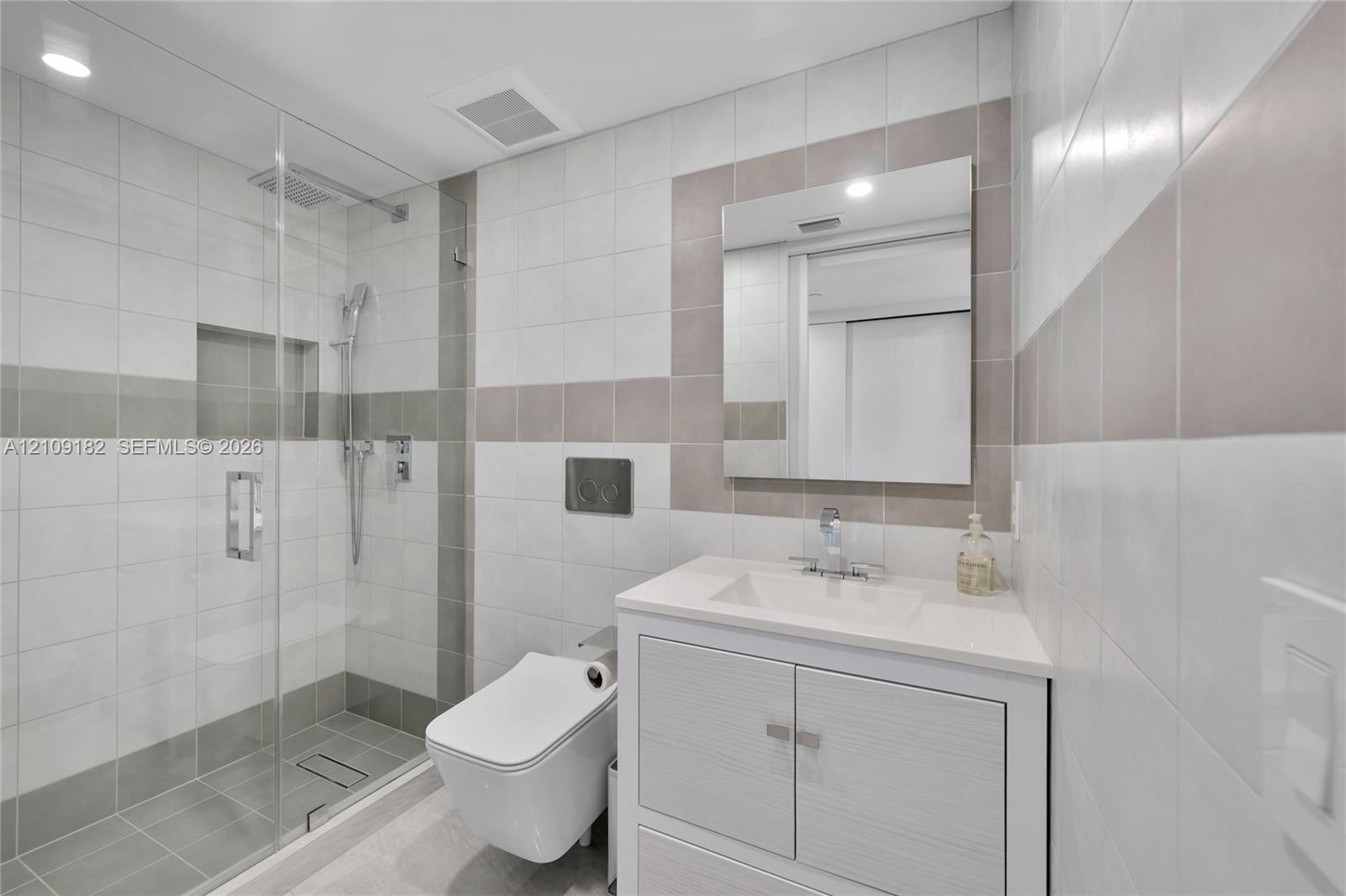 Bright interior featuring large-format tile flooring, expansive floor-to-ceiling windows, custom white built-in cabinetry, and integrated desk workspa