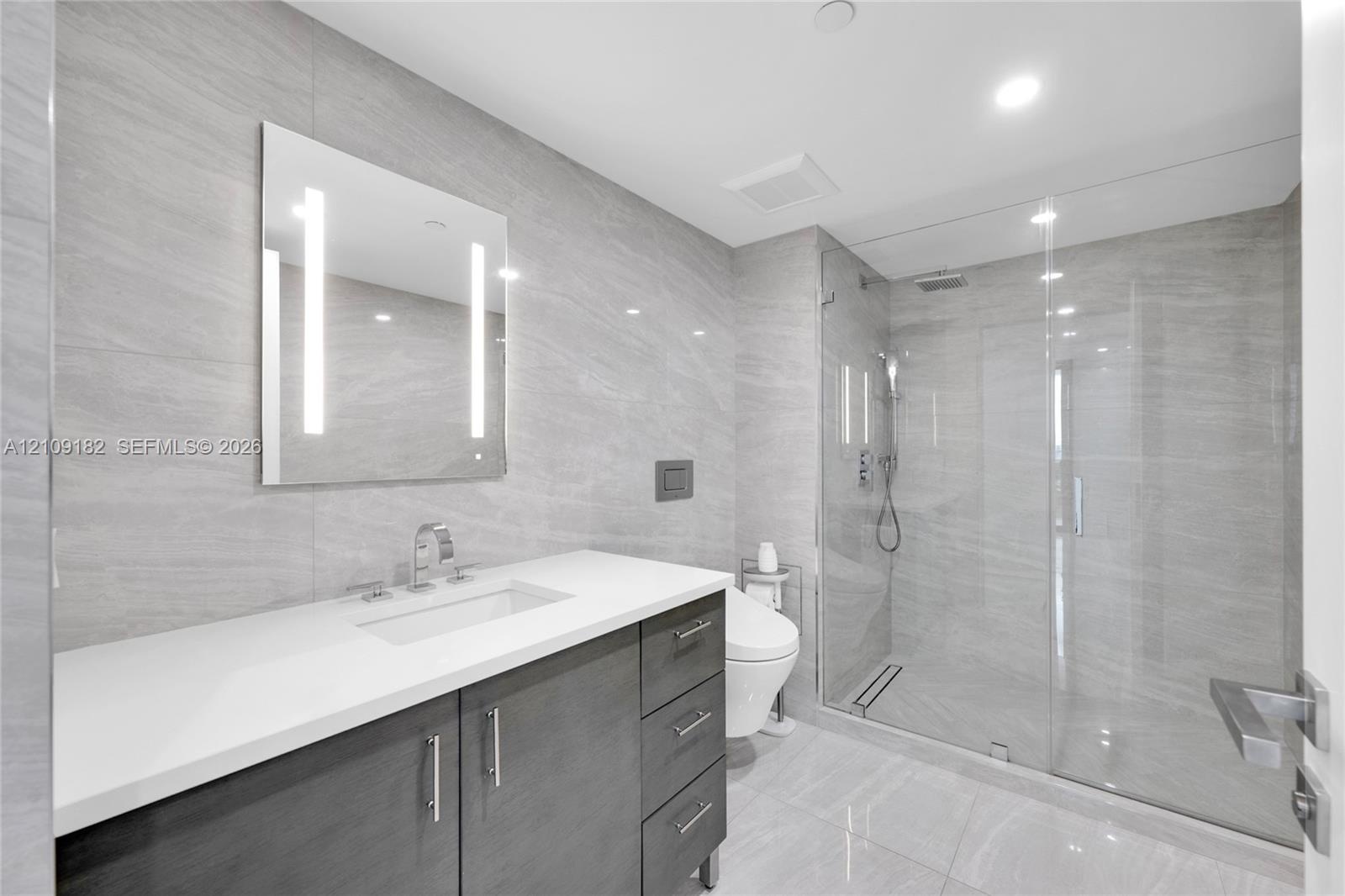 Customized walk-in closet featuring floor-to-ceiling built-in shelving, a central storage island with soft-close drawers, recessed ceiling lighting, a