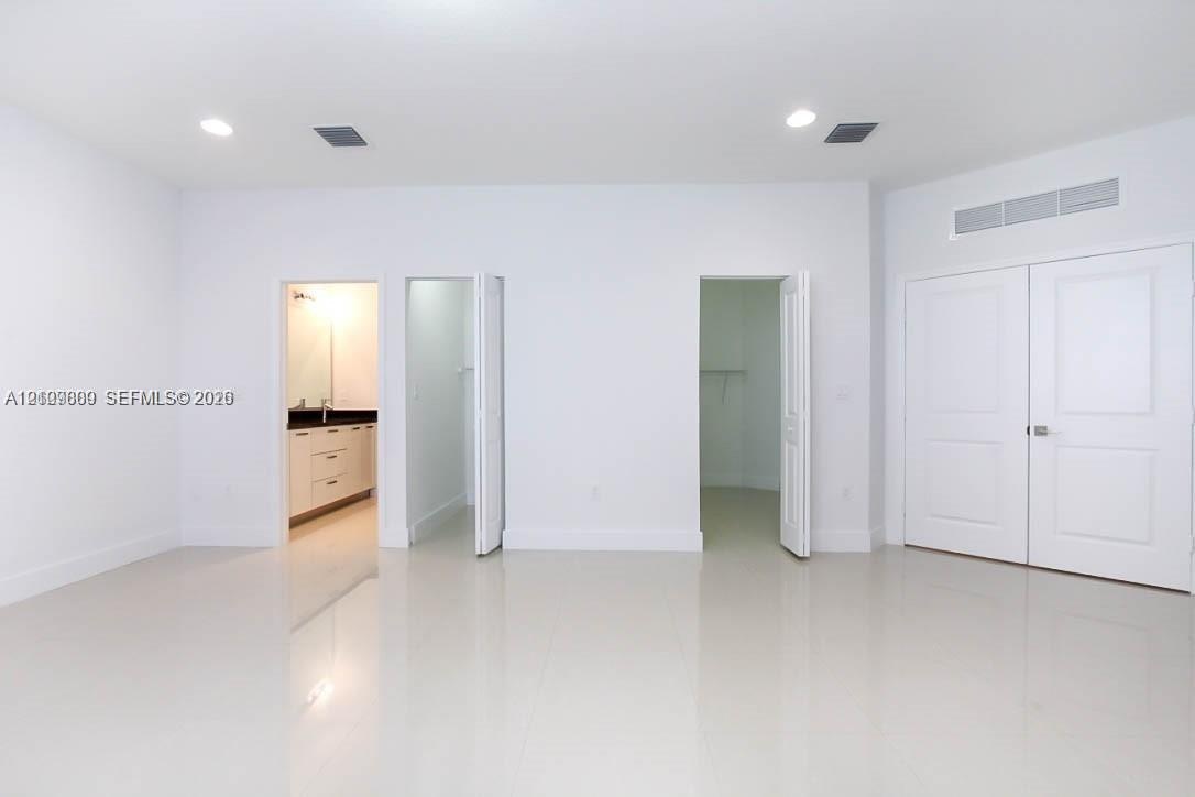 Neutral interior featuring large-format tile flooring, recessed ceiling lighting, two walk-in closets, and dual-panel interior doors