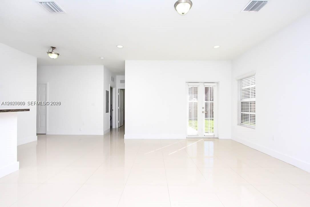 Open-concept interior featuring light-toned tile flooring, recessed lighting, flush-mount ceiling fixtures, and French doors