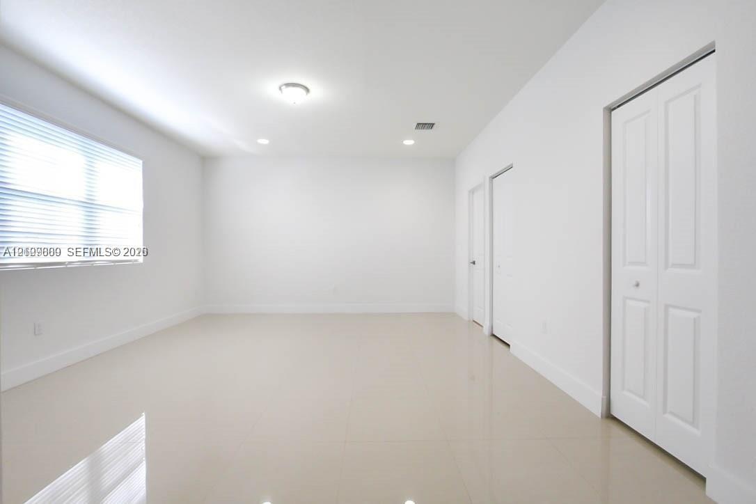 Interior room featuring light-toned tile flooring, recessed lighting, horizontal window blinds, and dual-panel closet doors