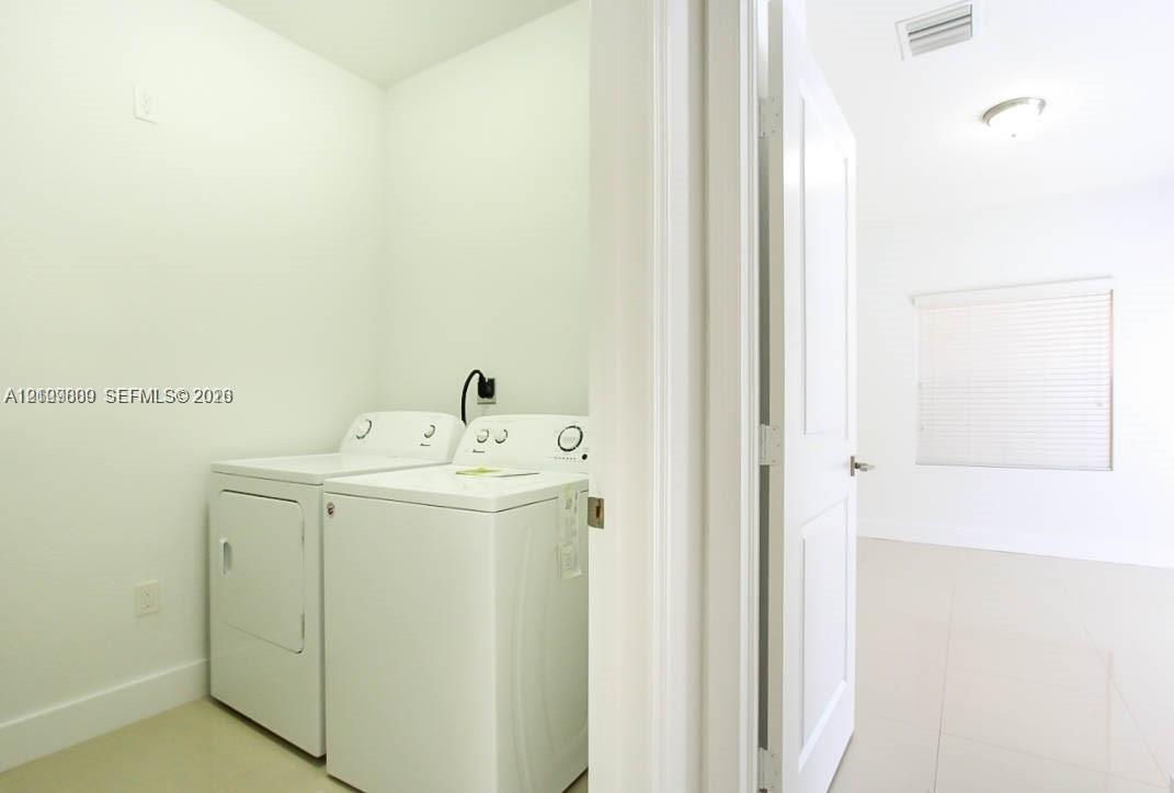 Utility area featuring neutral tile flooring, white walls, and a multi-panel interior door