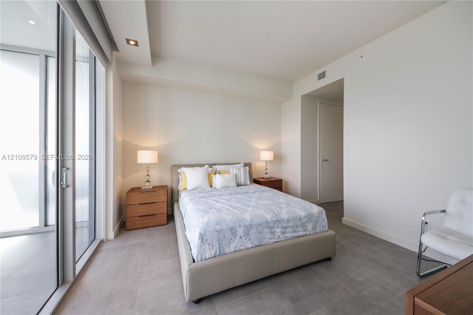 Floor-to-ceiling glass sliding doors, neutral tile flooring, recessed ceiling lighting, and smooth-finish interior walls