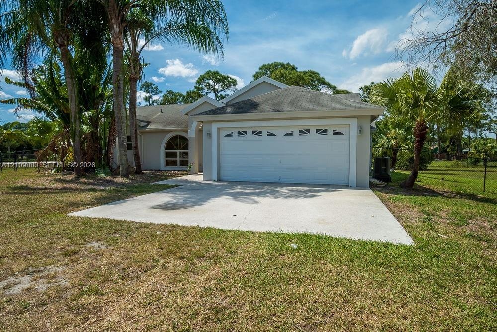 Single-story exterior featuring a concrete driveway, two-car garage with arched decorative windows, and stucco siding
