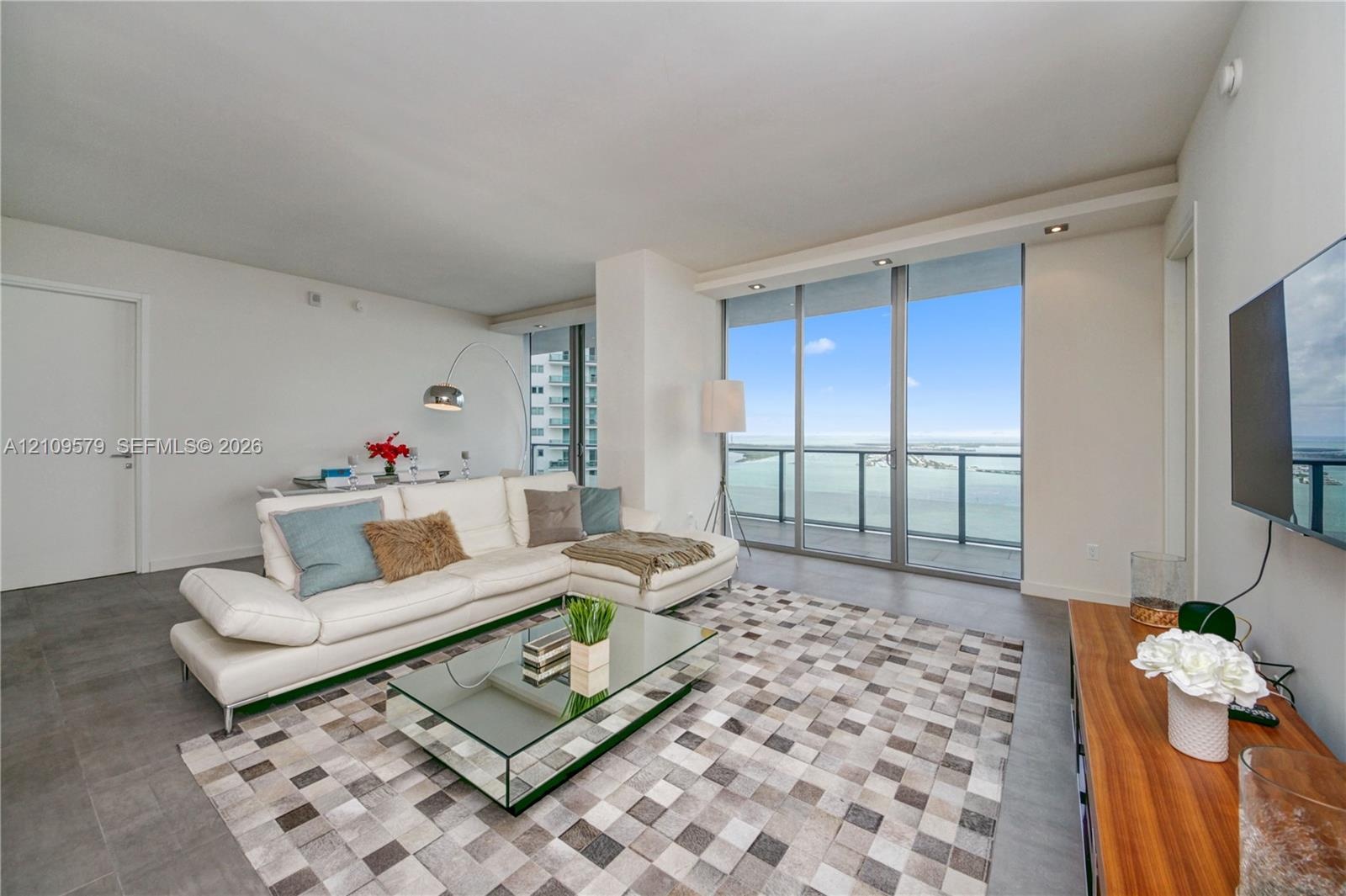 Floor-to-ceiling glass windows, recessed ceiling lighting, and large-format tile flooring