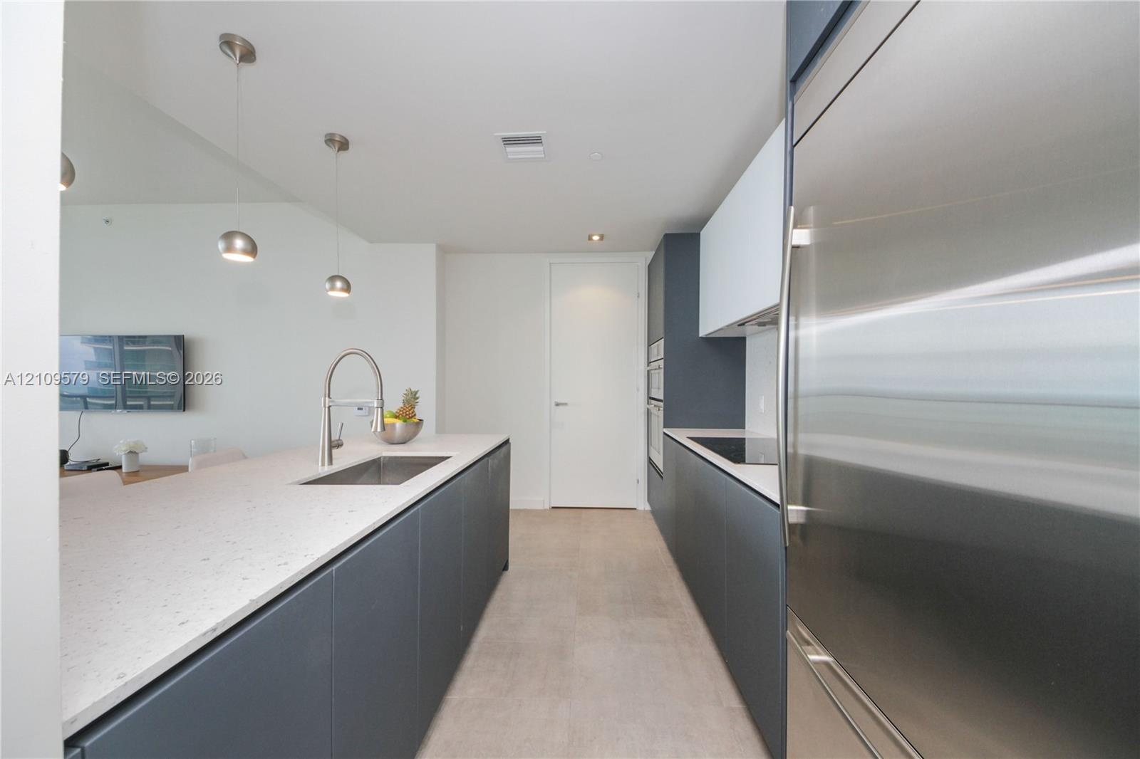 Modern kitchen featuring matte charcoal cabinetry, light-toned composite countertops, a stainless steel undermount sink with a high-arc pull-down fauc