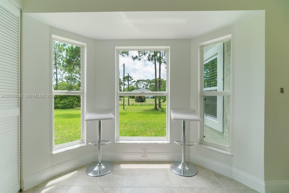 Bay window with triple-pane windows, neutral stone-finish tile flooring, and white louvered closet doors