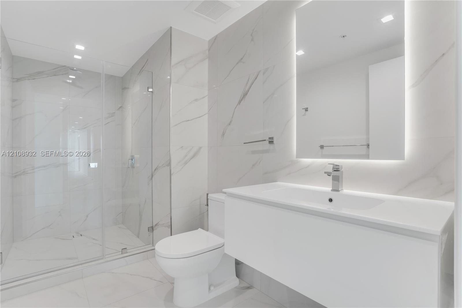 Modern bathroom featuring floor-to-ceiling large-format stone-patterned tile, a glass-enclosed walk-in shower, a white floating vanity with a seamless