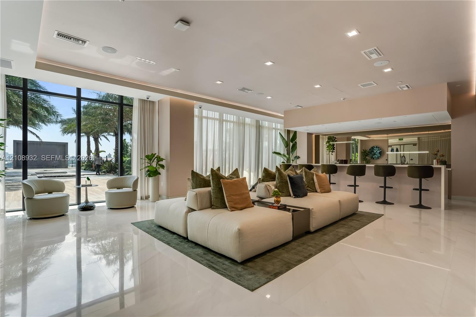Open-concept interior featuring floor-to-ceiling windows, polished stone flooring, recessed ceiling lighting, and a built-in bar area with stone count