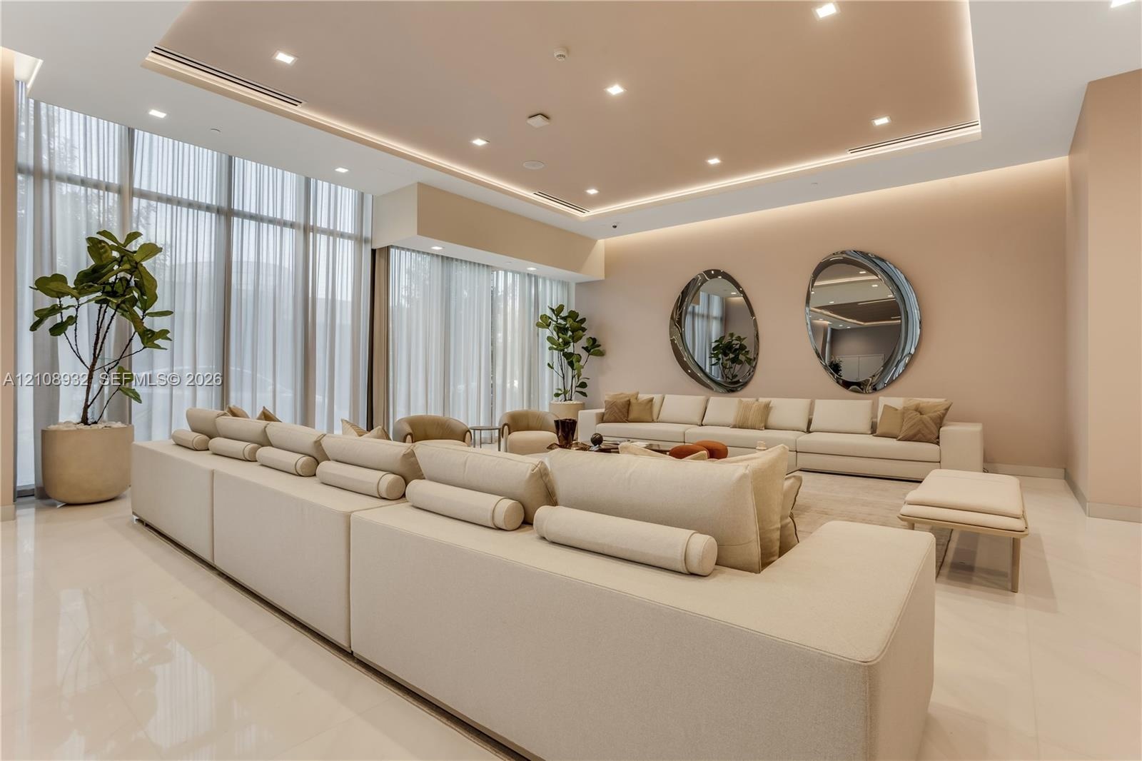 Floor-to-ceiling windows with floor-length drapery, recessed tray ceiling with integrated cove lighting, recessed ceiling lights, and polished stone f