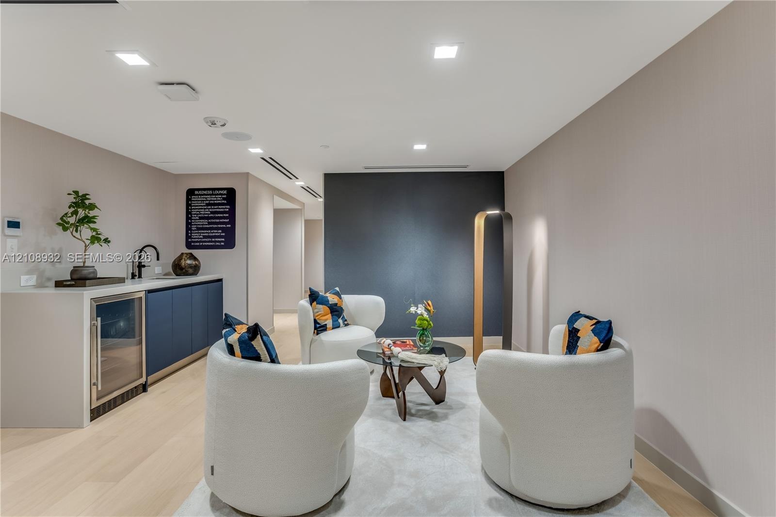 Wet bar featuring navy cabinetry, solid surface countertop, built-in beverage refrigerator, and matte black faucet, accented by recessed lighting and 