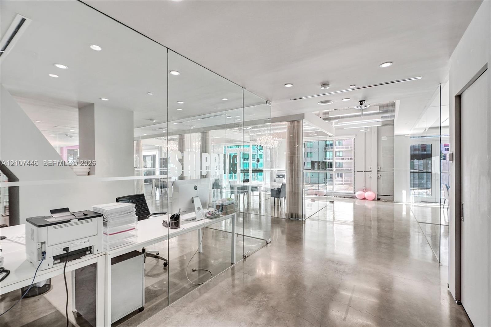 Expansive interior featuring polished concrete flooring, floor-to-ceiling glass wall partitions, and recessed ceiling lighting