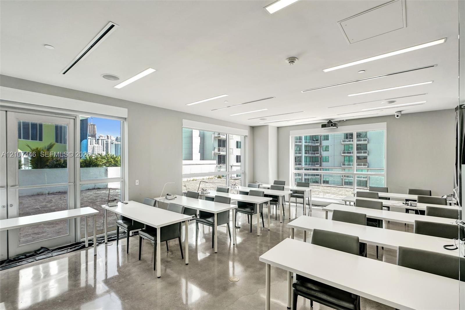 Expansive multi-use space featuring polished concrete flooring, recessed linear lighting, and large windows with glass-paned doors