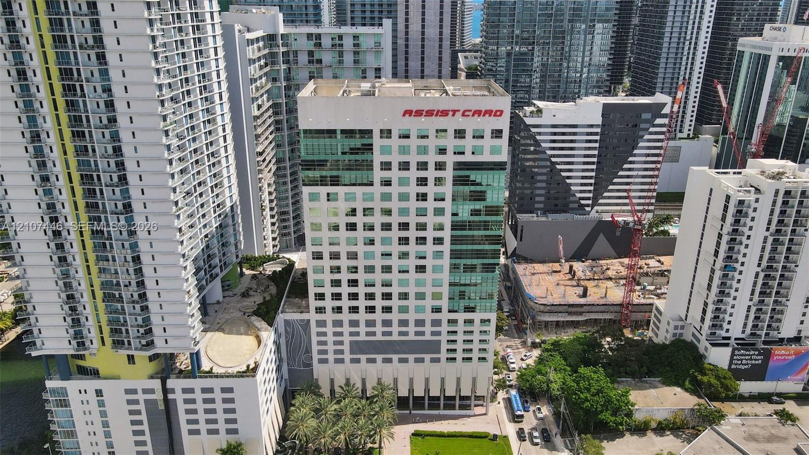 High-rise commercial building featuring a multi-story glass curtain wall, reinforced concrete facade, ground-level professional landscaping, and palm-