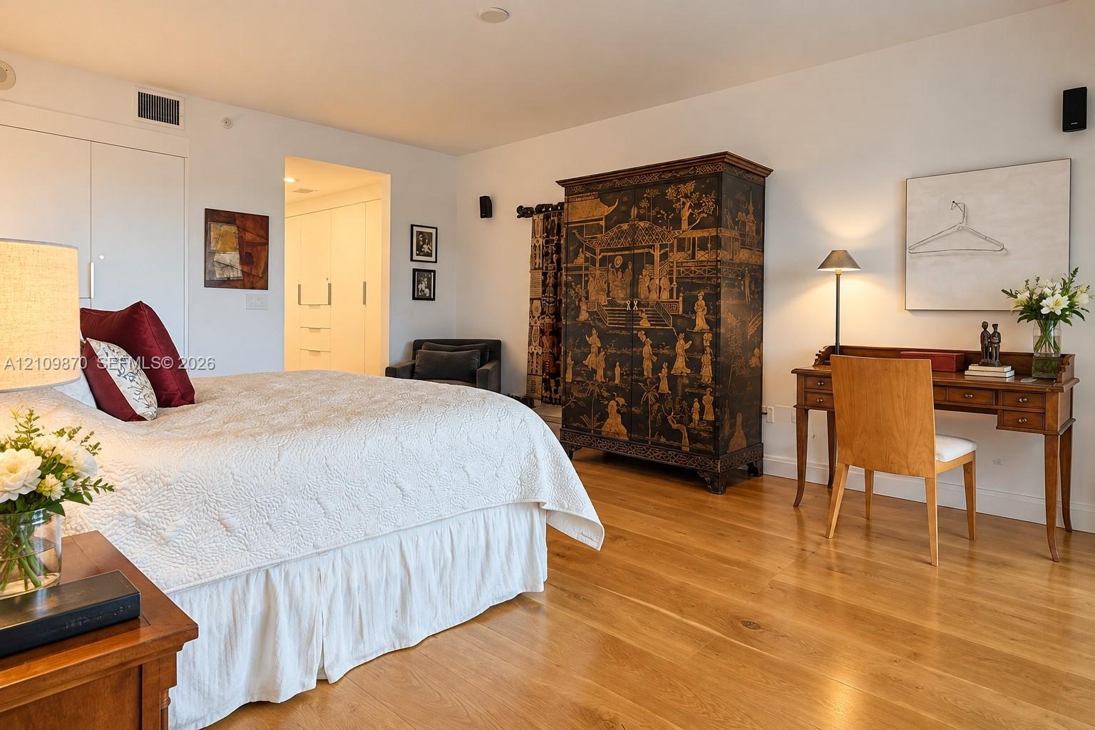 Room featuring wood-finish flooring, smooth-finish walls, and built-in closet cabinetry