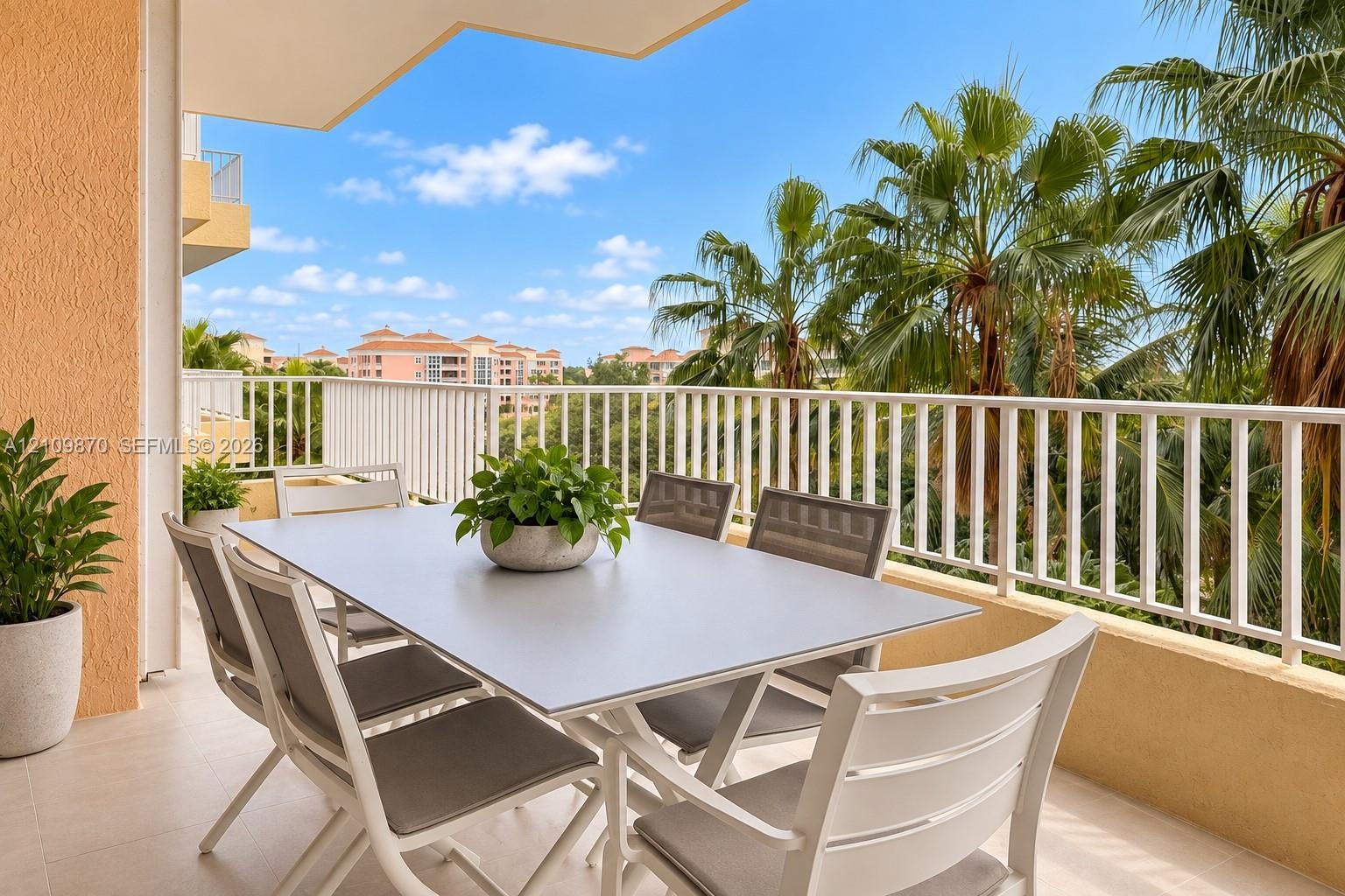 Covered balcony featuring neutral floor tile, stucco wall finishes, and a white vertical-bar railing