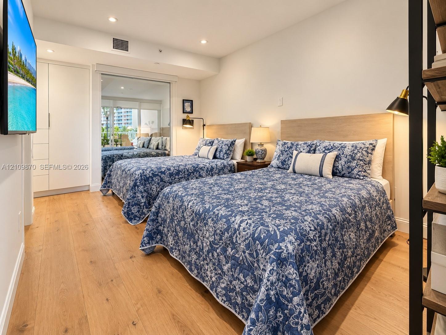Wood-finish flooring, recessed lighting, floor-to-ceiling built-in cabinetry, and a large sliding glass door