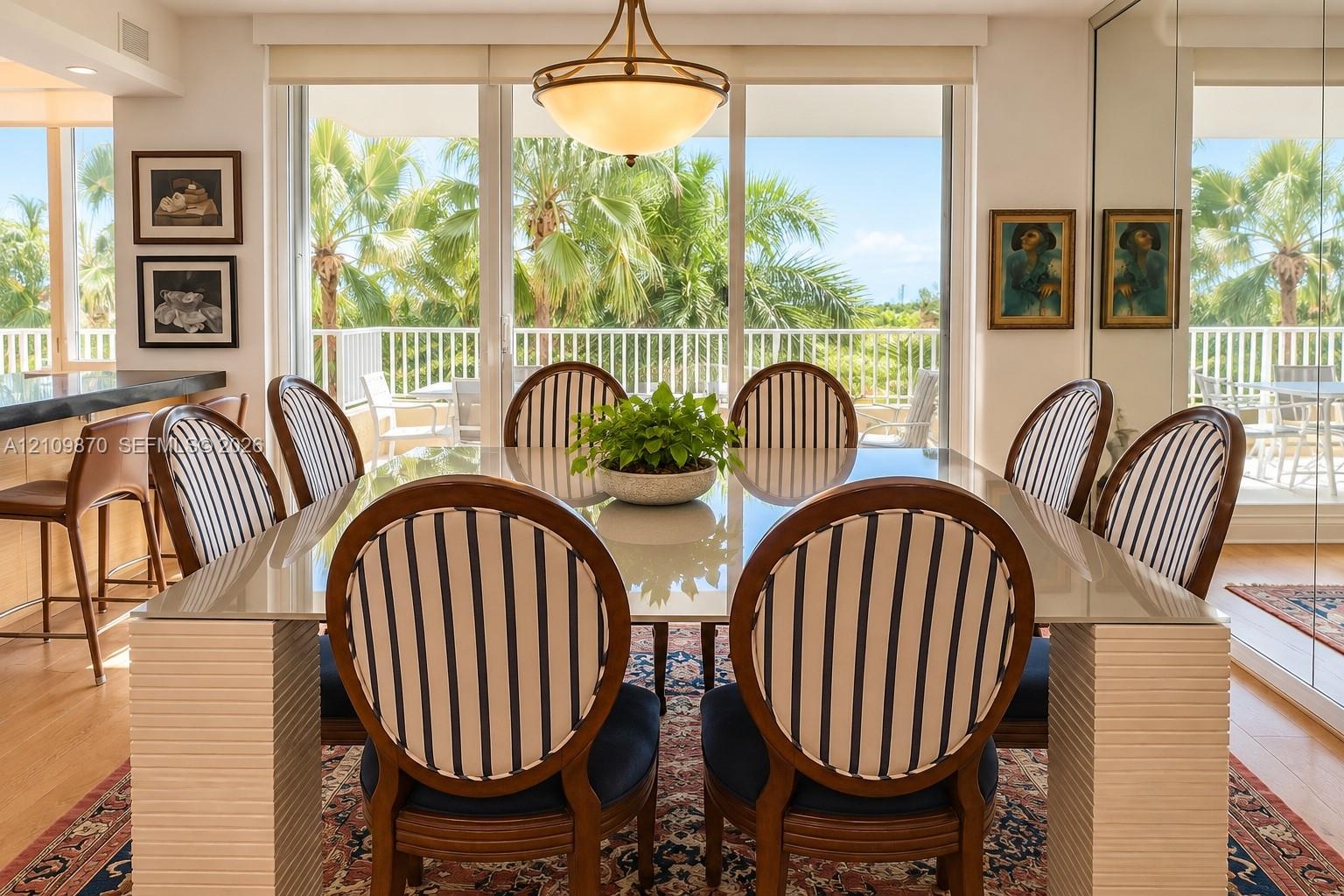 Dining area featuring floor-to-ceiling glass sliding doors, wood-finish flooring, a tiered metal pendant light fixture, and mirrored wall paneling