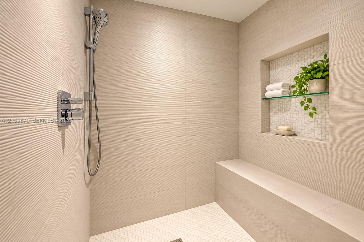 Walk-in shower featuring textured wall tile, a built-in stone bench, a recessed wall niche with glass shelving, and a multi-function handheld shower h
