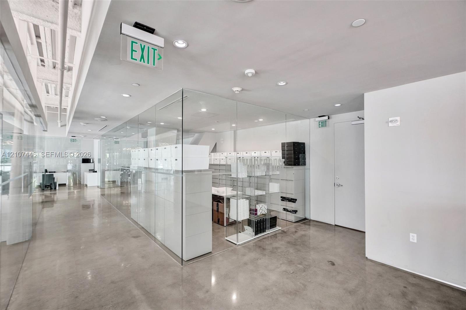 Polished concrete flooring, floor-to-ceiling glass wall partitions, recessed ceiling lighting, and exposed structural ceiling elements